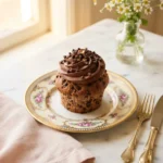 Foolproof choco chips cup cake with domed top and melted chocolate chips on a cream floral plate