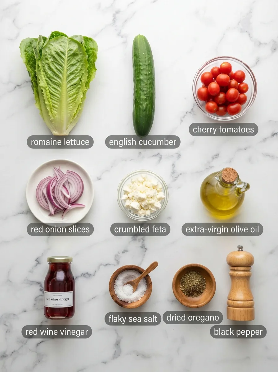 Ingredients for cucumber lettuce and tomato salad arranged on white marble