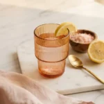 recipe pink salt trick drink in an amber glass with lemon wedge on a white marble surface