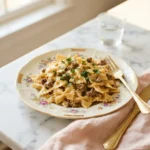 Creamy Velveeta beef pasta with bowtie noodles coated in golden cheese sauce on a floral plate
